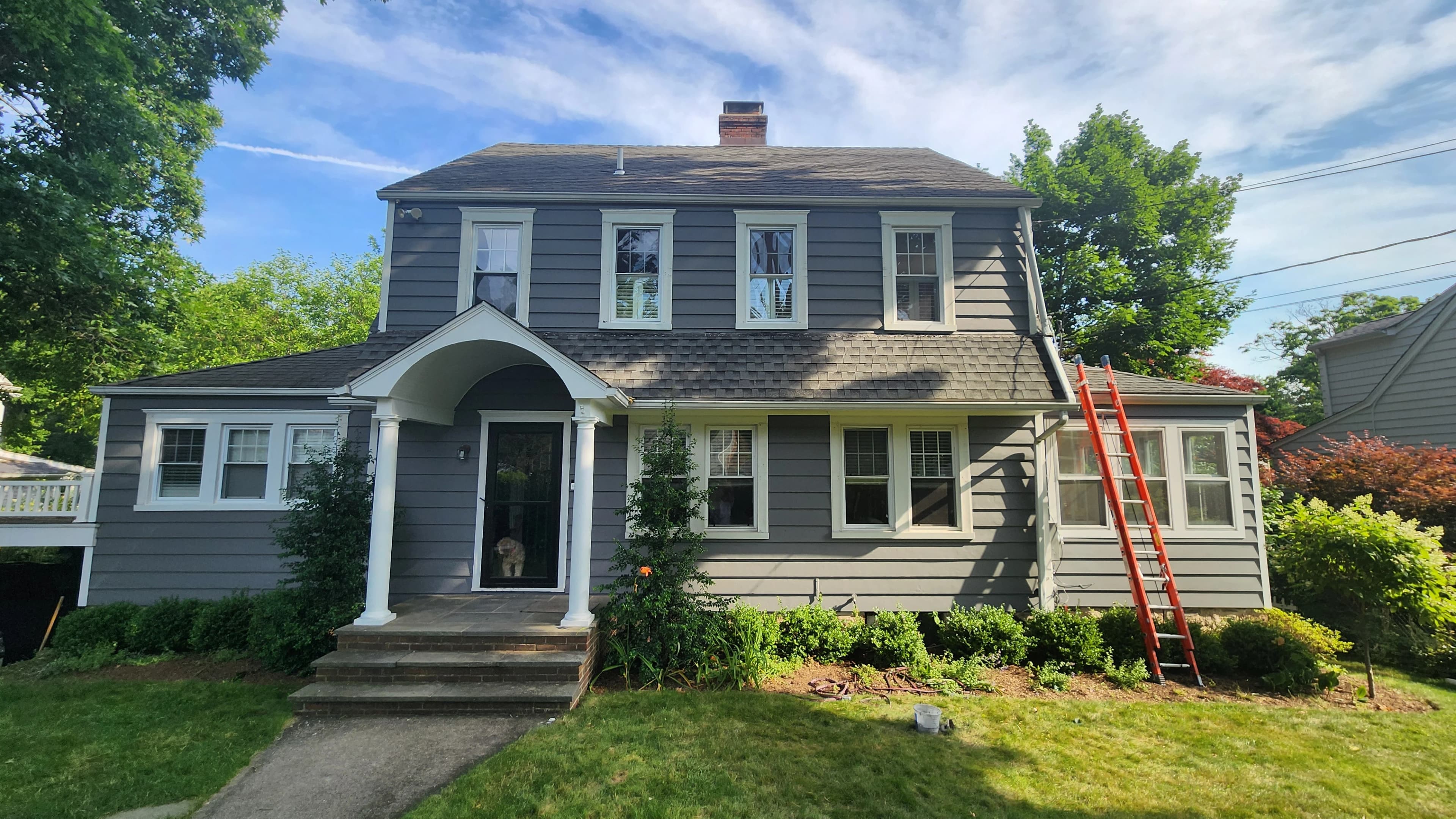 Front shot of a house after it has been painted with an orange ladder leaning against it